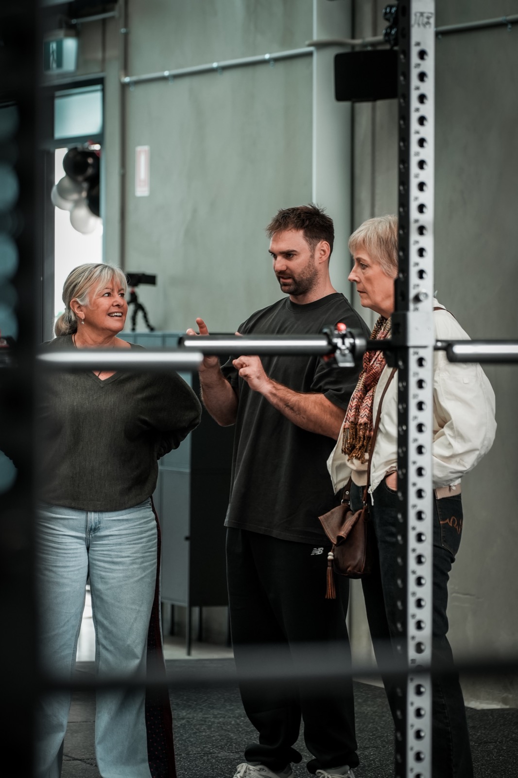 An RTB coach walking a member through her bar setup in the squat rack